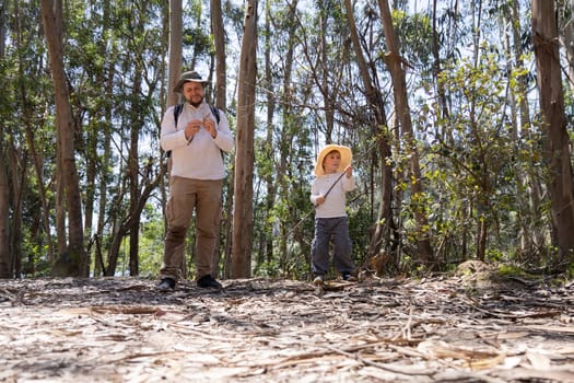 Father and son wearing straw hats enjoying a sunny day in a eucalyptus forest