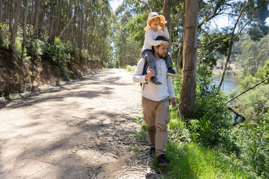 Father and son enjoying a leisurely walk in nature, surrounded by trees and a nearby river