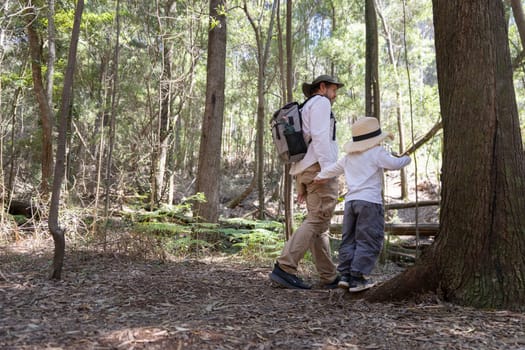 Father and son enjoying a hike in the woods, exploring nature and making memories together
