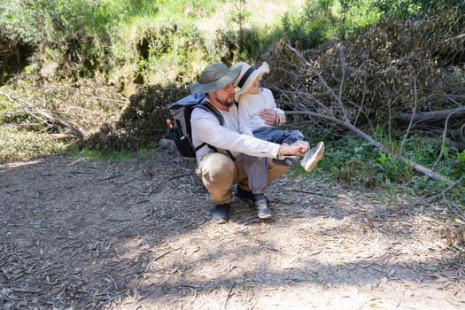 Father tying his child's shoelace during a hike in nature
