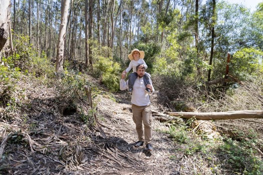 Father and son enjoying a hike through a sunny forest trail