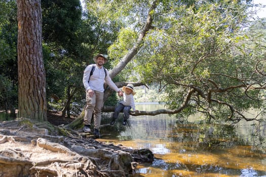 Father and son enjoying a sunny day by the lake, exploring nature and creating memories