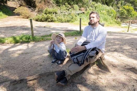 Father and son taking a break during a hiking trip, enjoying the peaceful surroundings