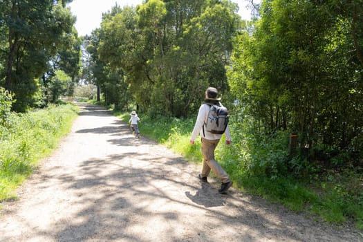 Father and son enjoying a leisurely hike through a sun-dappled forest path