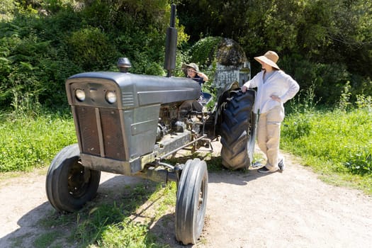 Farmers posing with their vintage tractor in a sunny countryside field