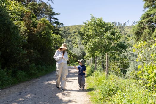 Mother and son walking on a dirt road, enjoying a sunny day in nature