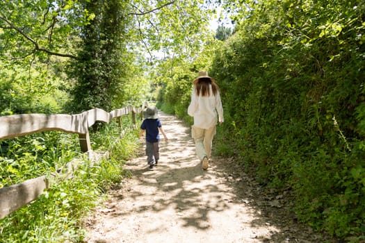 Mother and son enjoying a leisurely stroll through a sunny forest path