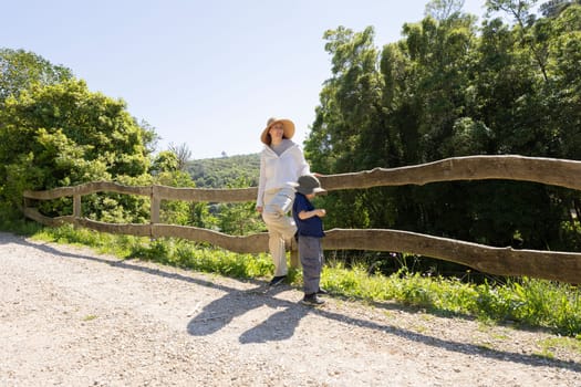 Mother and son taking a break during hike, leaning on wooden fence overlooking valley
