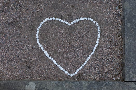A heart shape formed from smooth stones is placed gently on a grave, symbolizing love and remembrance.