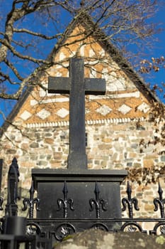 A peaceful Lutheric cemetery in Finland, featuring a solitary grave marked by a stone cross. The surroundings are calm and reflect a quiet, respectful atmosphere