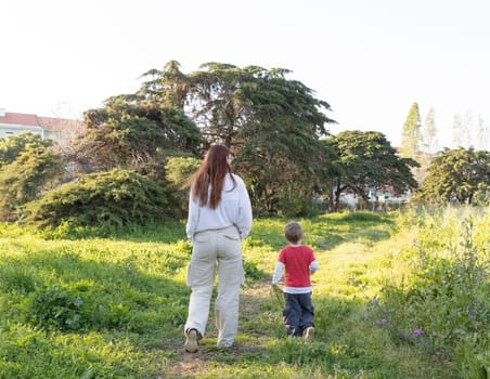 Mother and son enjoying a peaceful walk through nature, surrounded by lush greenery and trees