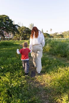 Mother and son enjoying a leisurely stroll through a vibrant green meadow, creating cherished memories amidst nature's embrace