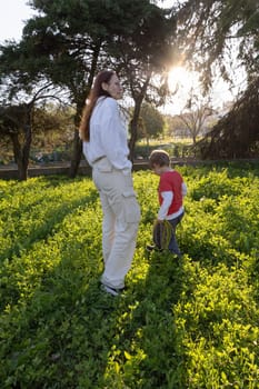 Mother and her son enjoying a walk through a green field at sunset