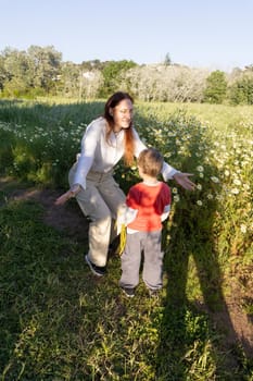 Mother and son sharing a tender moment in a field of daisies, enjoying the warm spring sunlight