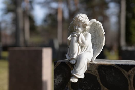 A peaceful Lutheric cemetery in Finland, featuring a solitary grave marked by a stone angel. The surroundings are calm and reflect a quiet, respectful atmosphere