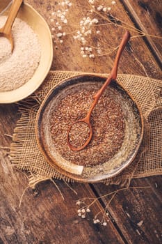 Shredded flax seeds and heap of psyllium husk (Isabgol) in a bowl on wooden table