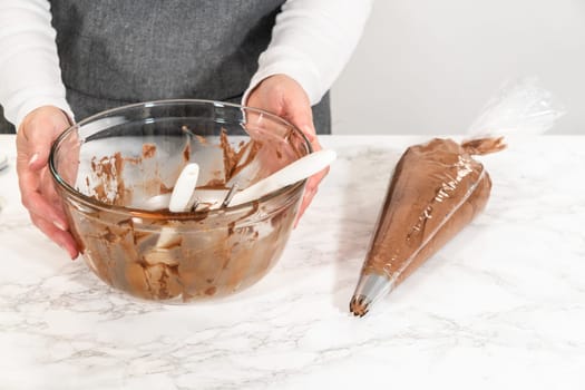 The chocolate icing is carefully transferred into a piping bag, ready to adorn the scrumptious cupcakes.