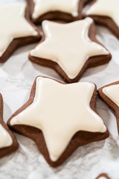 A neat arrangement of gingerbread star cookies covered in white royal icing, emphasizing their festive and uniform design.