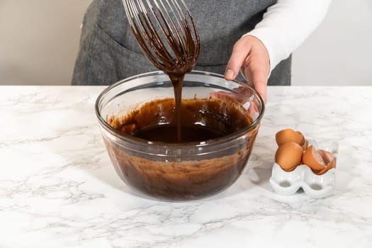In the process of creating mouthwatering chocolate cupcakes, the first step involves meticulously mixing the ingredients in a glass mixing bowl to make the perfect batter.