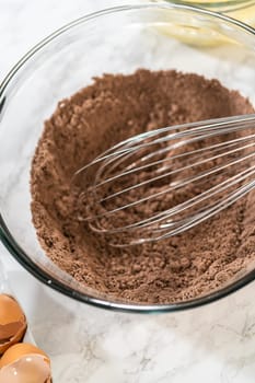 In the process of creating mouthwatering chocolate cupcakes, the first step involves meticulously mixing the ingredients in a glass mixing bowl to make the perfect batter.