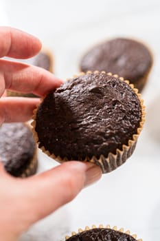 Freshly baked chocolate cupcakes are poised for a delightful transformation as they await a generous coating of rich and velvety chocolate frosting.