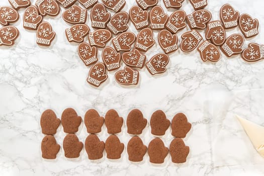 Rows of both decorated and plain mitten cookies are arranged together, highlighting the transition from unadorned to beautifully iced holiday cookies.