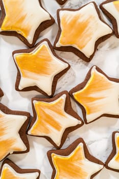 A collection of gingerbread star cookies decorated with royal icing and painted with vibrant gold luster dust, beautifully arranged for a festive look.