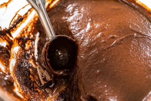 The process involves carefully scooping the rich batter into the waiting cupcake pan.