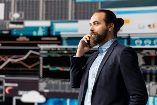 Professional businessman answering a phone call surrounded by KPI metrics to evaluate company performance and insight. Using remote communication to improve his business, greatness.