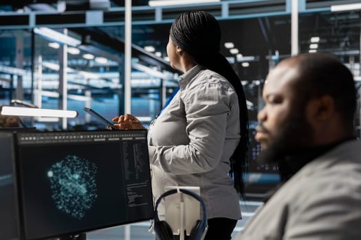 Data center employee monitoring system performance using PC, identifying malfunctions. African american server farm IT expert troubleshooting computer bugs, implementing optimizations