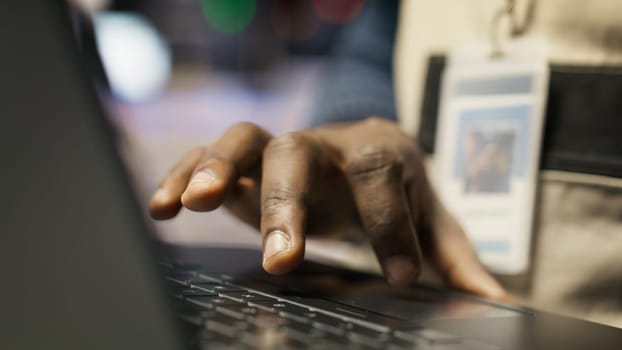 Engineer in smart factory oversees robotic assembly lines using laptop software, ensuring quality control. Worker monitoring automated conveyor systems using notebook program, camera B closeup
