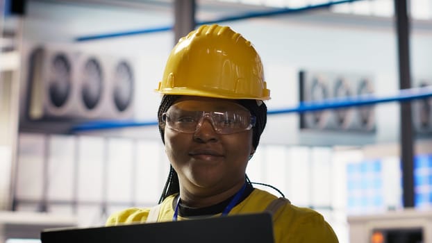 Smiling smart factory specialist testing automated systems to ensure reliability. Happy engineer in industry 4.0 industrial plant identifying bottlenecks and optimizing gear based on data, camera B