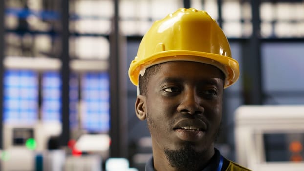 Close up of professional testing equipment in industry 4.0 plant producing renewable energy. African american man in photovoltaics smart factory conducting routine inspection, camera B