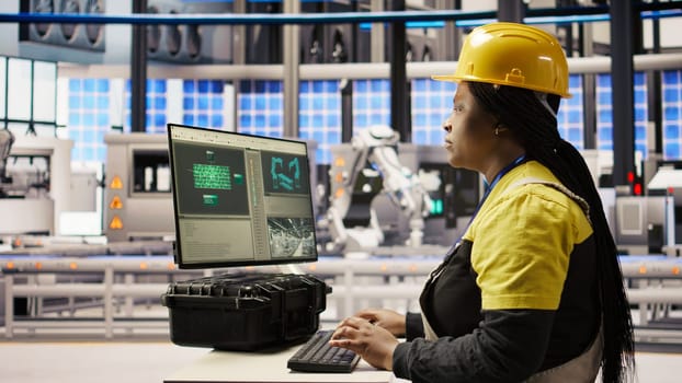 Engineer in photovoltaics factory using PC display to look at system performance metrics. Worker in industry 4.0 plant using computer screen to track energy production through IoT sensors, camera A
