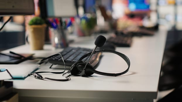 Audio equipment headset with mic used in customer support job workspace, close up. Headphones with microphone on call center company office desk used by workers to discuss with customers