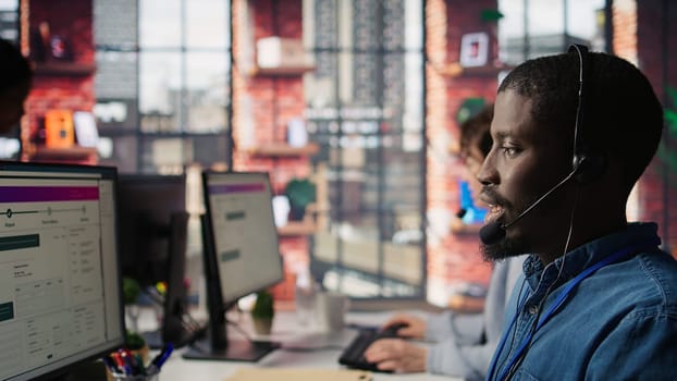 Diverse customer center workers assisting clients with installing software. Multiethnic team of call center agents using remote access tools to connect to customer devices, fixing errors, camera B