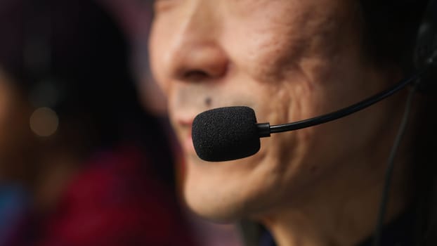 Closeup of experienced worker talking with customer using headphones mic to gain new sales. Asian account manager in office using audio headset, speaking with client to generate leads, camera A