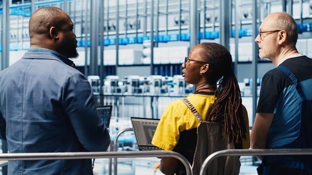 Manager supervising photovoltaic smart factory workers designing production lines in CAD software. Industry 4.0 solar panels plant team leader overseeing employees optimizing floor layouts, camera A