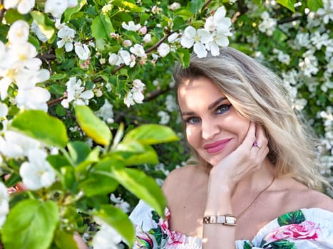 A mature blonde woman poses among blooming flowers, capturing a joyful moment for her lifestyle blog in a sunny garden.