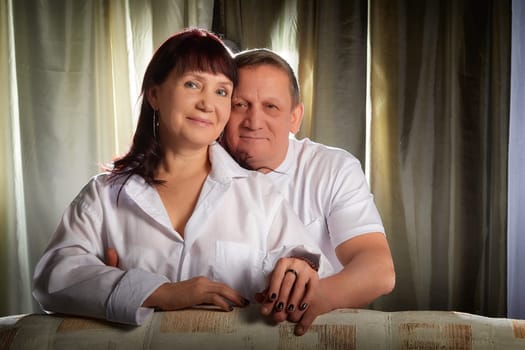 Middle-aged couple enjoys an affectionate moment in their apartment, celebrating their love during a cozy indoor photoshoot.