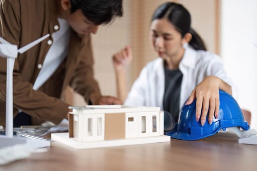 Two architects analyze eco-friendly building models and plans, emphasizing environmental responsibility and innovation.