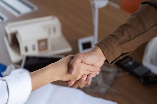 A close-up of two architects shaking hands, symbolizing their commitment to sustainable design and ESG principles.