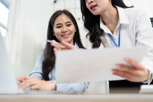 A professional woman shares insights and documents with her colleague, highlighting teamwork and effective communication.