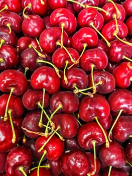 Freshly harvested ripe cherries piled closely together, showcasing their vibrant red color and texture.