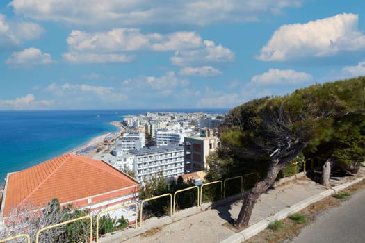 Rhodes. Greece - June 06, 2025: Elevated perspective of Rhodes beach, showing the extent of the coastline and city buildings. The contrast of the blue sea and sky with the sand.