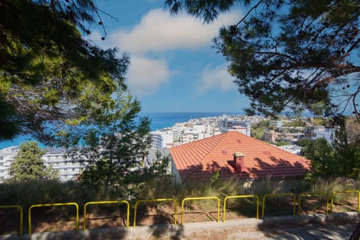 Rhodes. Greece - June 06, 2025: Views from Monte Smith of the Rhodes coastline, with the beach and city in the foreground. The Aegean Sea shines under a clear sky. White buildings and palm trees adorn the urban landscape.