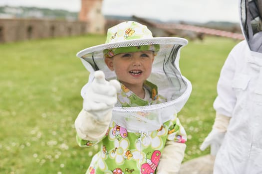 A beekeeper child in apiary in a protective suit