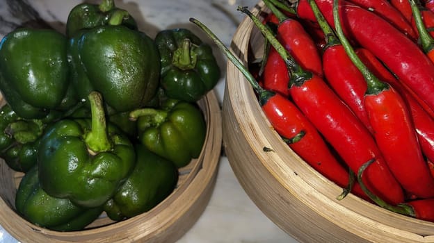 Vibrant red chili peppers and fresh green bell peppers arranged in bamboo bowls creating a colorful display perfect for food themes, cooking, healthy eating, and agricultural or culinary content.