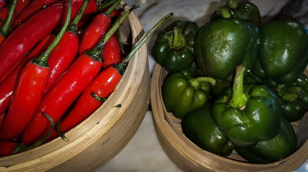 Vibrant red chili peppers and fresh green bell peppers arranged in bamboo bowls creating a colorful display perfect for food themes, cooking, healthy eating, and agricultural or culinary content.
