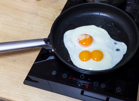 Fried eggs on the pan one of them with double egg egg yolk
